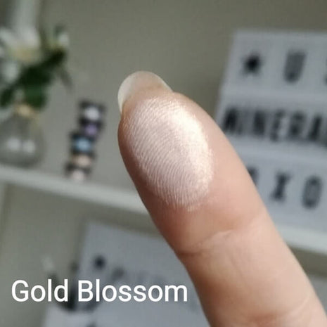 Schimmernder Swatch von Gold Blossom auf der Fingerspitze